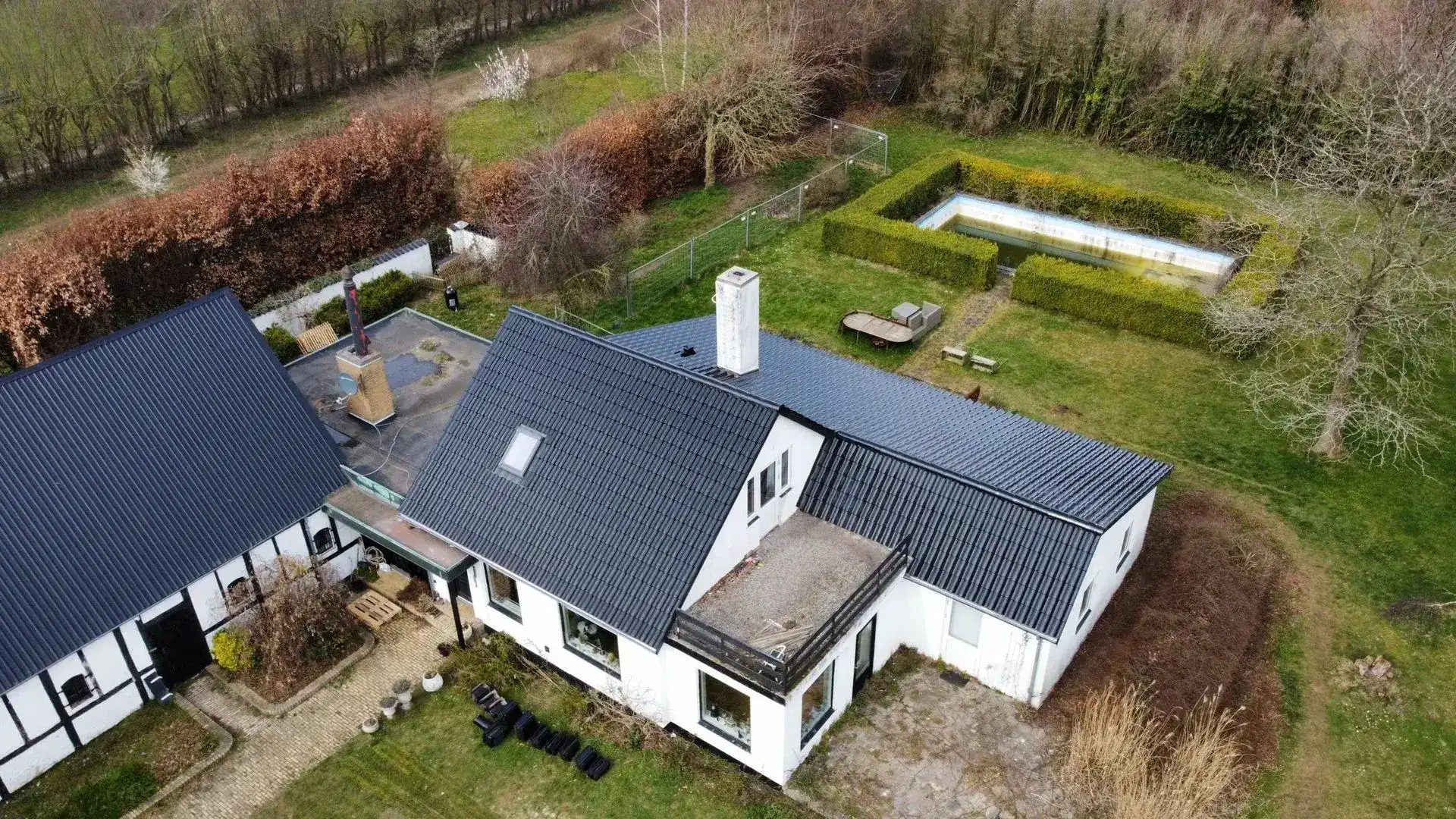 Luftfoto af moderne hus med stor have og udendørsarealer.