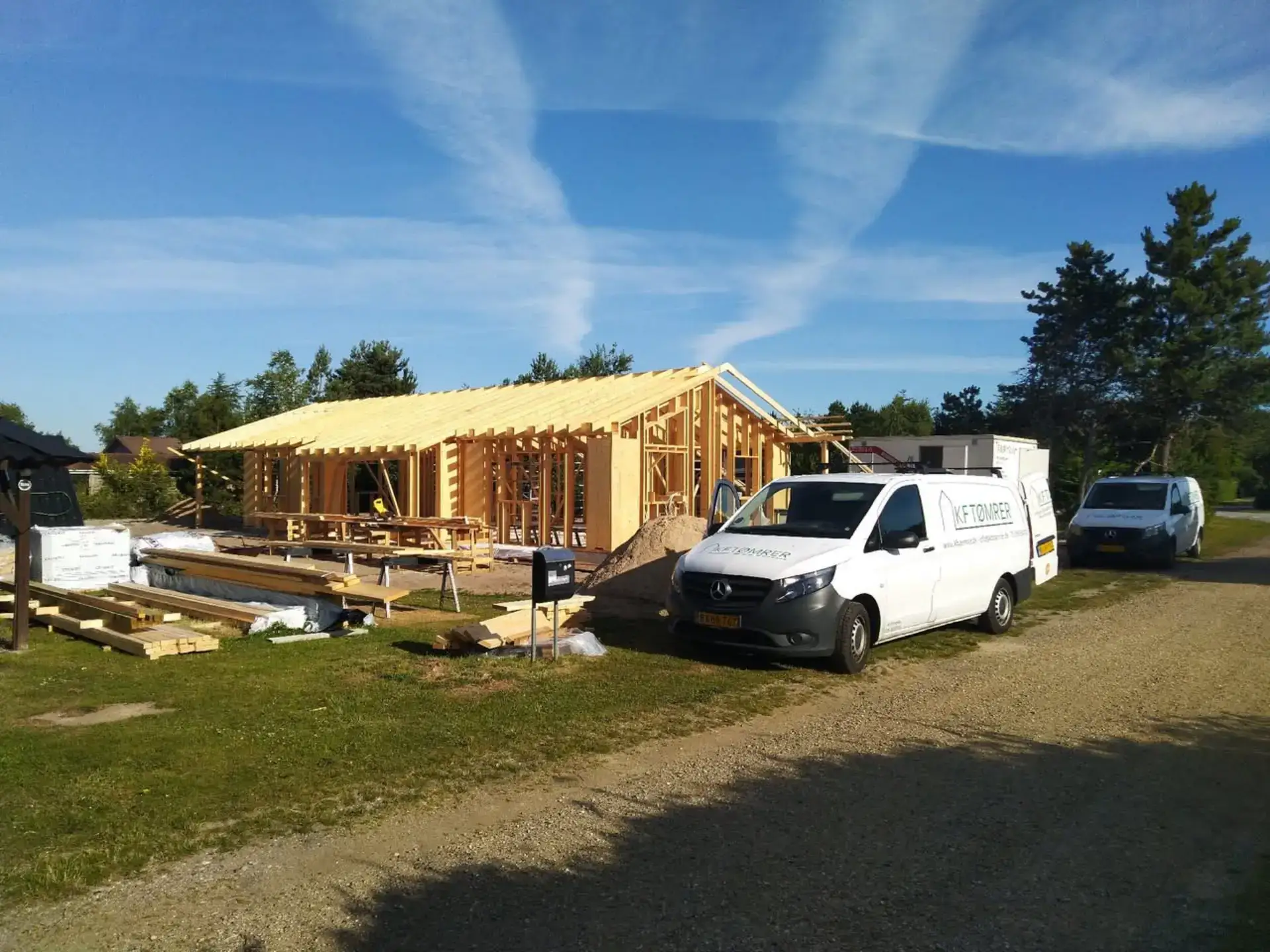 Konstruktion af træhus med synlige trærammer og byggeudstyr.